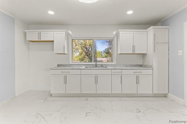 kitchen with light stone countertops, white cabinetry, and sink