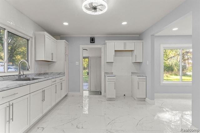 kitchen featuring white cabinetry, sink, light stone countertops, and ornamental molding