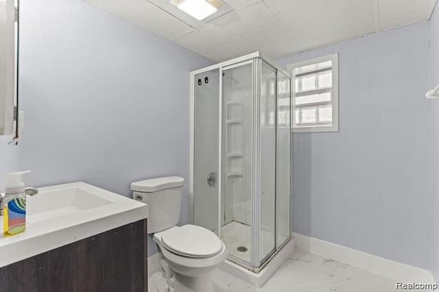 bathroom featuring vanity, a drop ceiling, toilet, and a shower with shower door