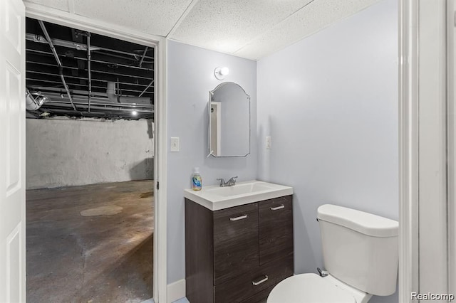 bathroom featuring a drop ceiling, vanity, and toilet