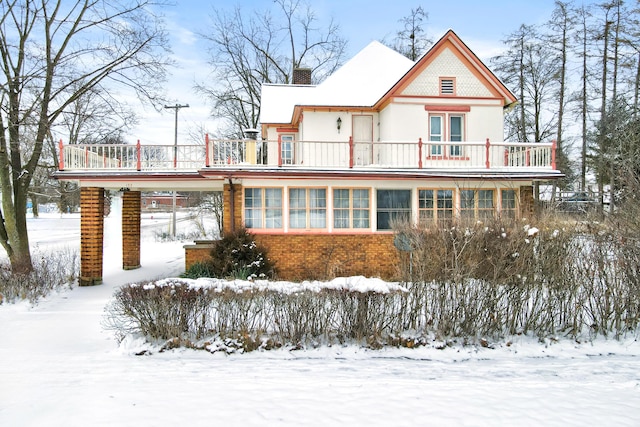 snow covered house featuring a balcony