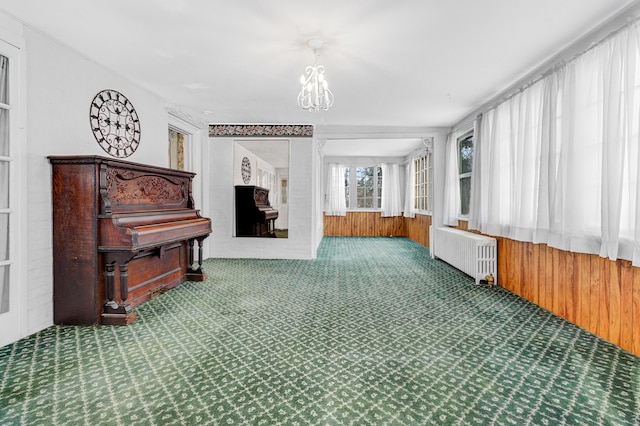 interior space with a notable chandelier, radiator, and wooden walls