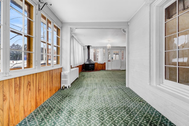 interior space featuring wooden walls, radiator heating unit, carpet, and a wealth of natural light