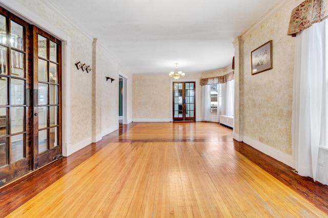 spare room featuring french doors, crown molding, an inviting chandelier, and hardwood / wood-style flooring