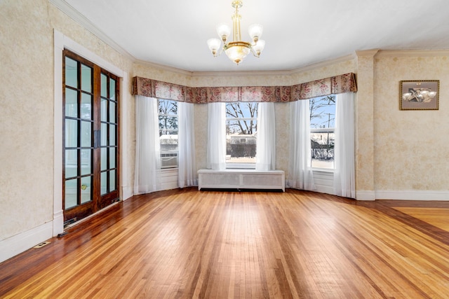 spare room with radiator, crown molding, baseboards, a notable chandelier, and wood-type flooring