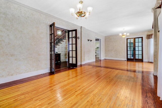 empty room with a chandelier, crown molding, baseboards, and hardwood / wood-style flooring