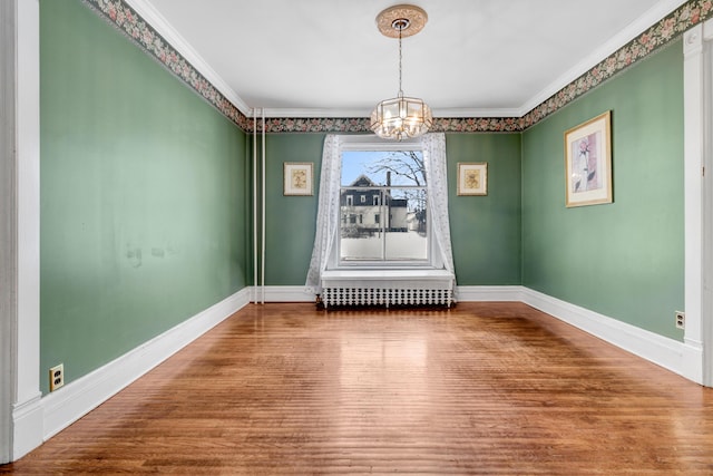 unfurnished dining area featuring baseboards, crown molding, an inviting chandelier, and wood finished floors