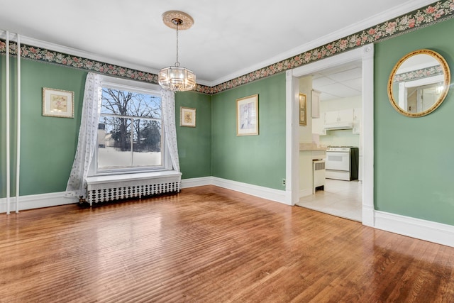 empty room with baseboards, an inviting chandelier, wood finished floors, and ornamental molding