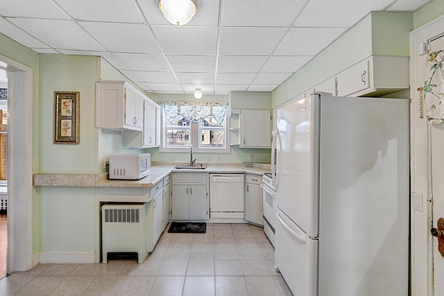 kitchen featuring a paneled ceiling, radiator, white appliances, sink, and white cabinets