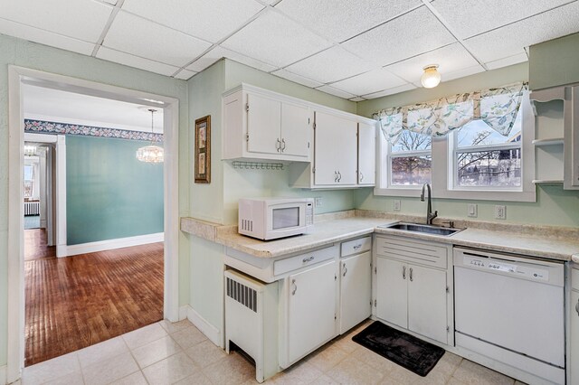 kitchen featuring white appliances, light countertops, a paneled ceiling, and a sink