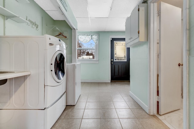 laundry room featuring light tile patterned floors, laundry area, washing machine and dryer, and baseboards