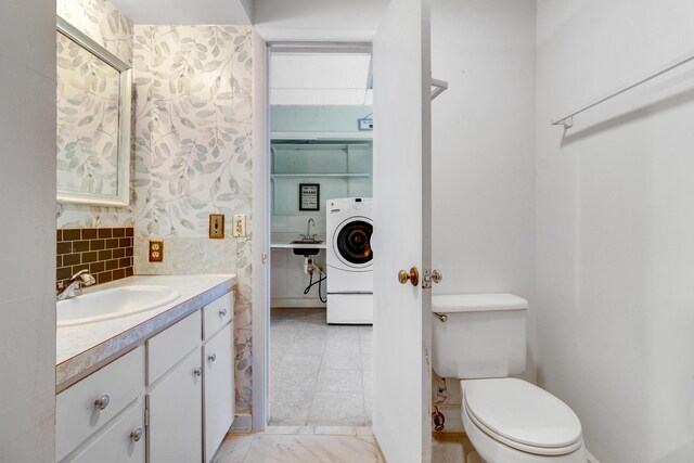 bathroom with vanity, toilet, washer / dryer, and tasteful backsplash