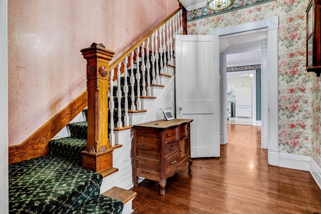 staircase featuring wallpapered walls, wood finished floors, and baseboards