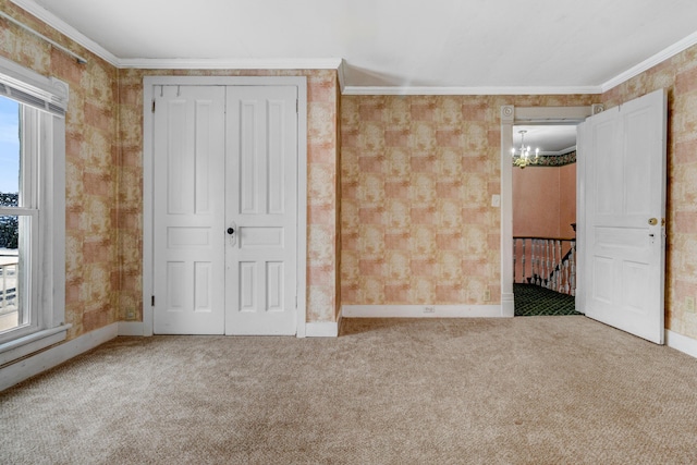 unfurnished bedroom with carpet floors, an inviting chandelier, a closet, and crown molding