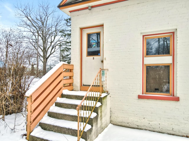 snow covered property entrance with brick siding