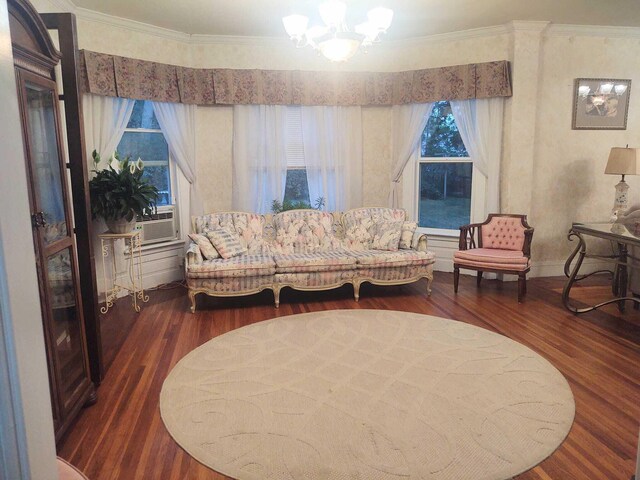 living area featuring cooling unit, an inviting chandelier, wood finished floors, and crown molding