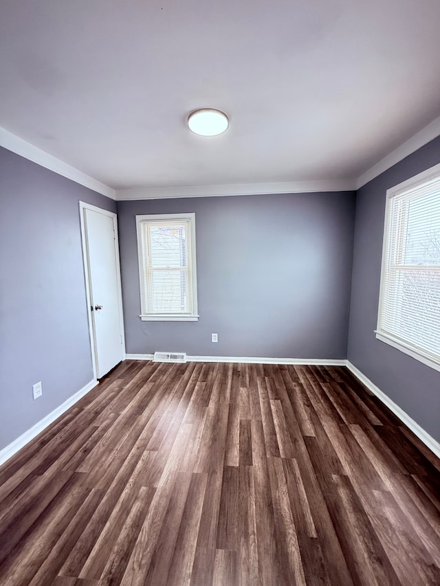 unfurnished room with crown molding and dark wood-type flooring