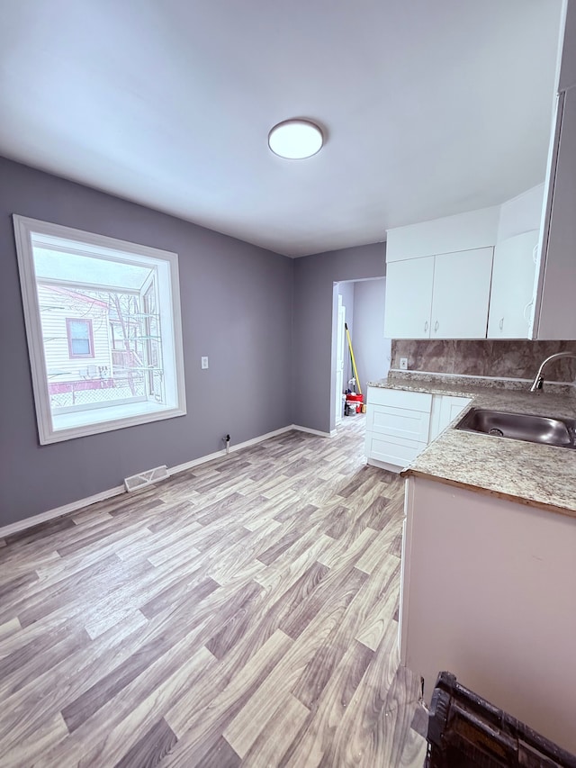 kitchen featuring light hardwood / wood-style floors, white cabinetry, sink, and tasteful backsplash