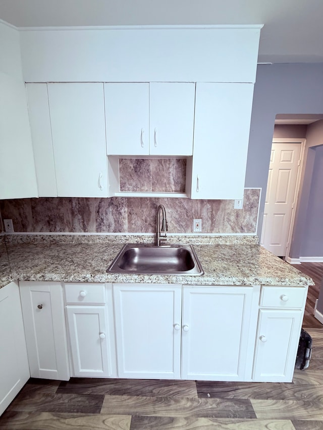 kitchen with white cabinetry, sink, tasteful backsplash, light stone counters, and wood-type flooring