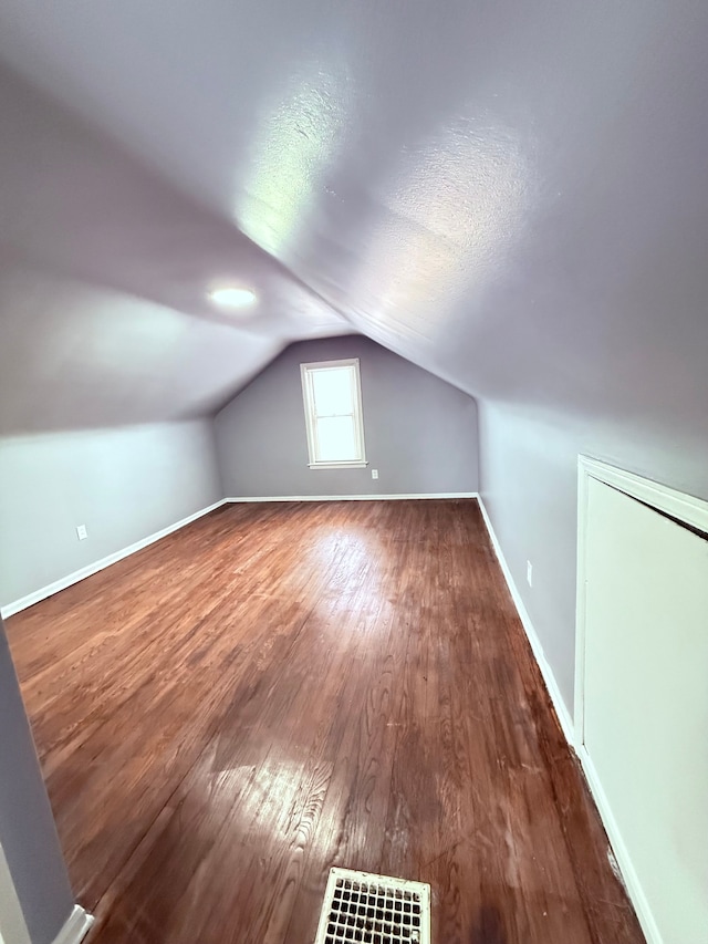 bonus room featuring vaulted ceiling and dark wood-type flooring