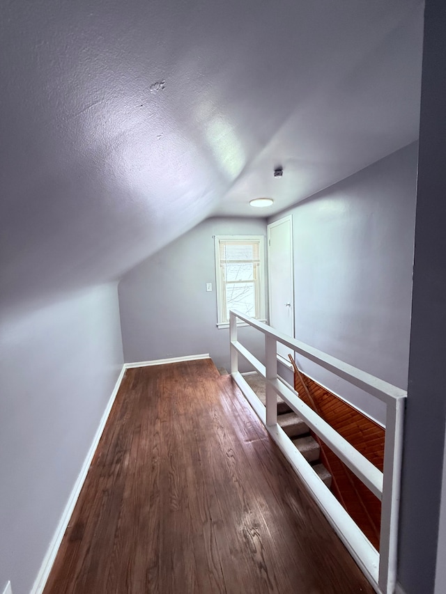 bonus room featuring dark wood-type flooring and vaulted ceiling