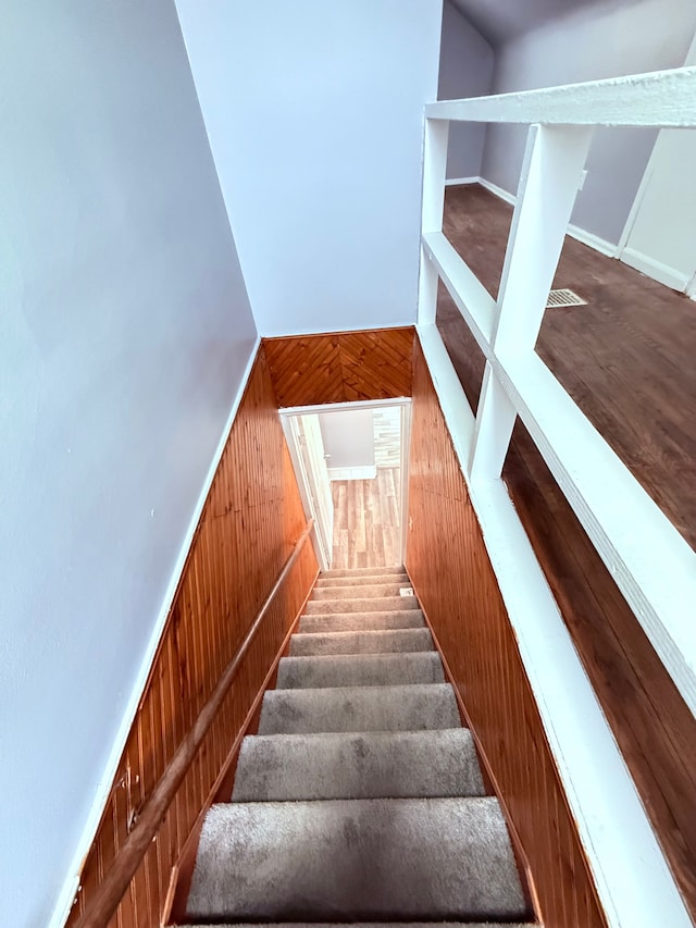 staircase featuring wood walls