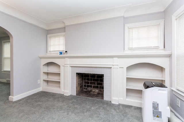 unfurnished living room with carpet, a healthy amount of sunlight, ornamental molding, and a brick fireplace