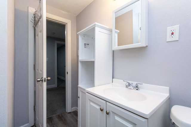 bathroom with hardwood / wood-style flooring, vanity, and toilet