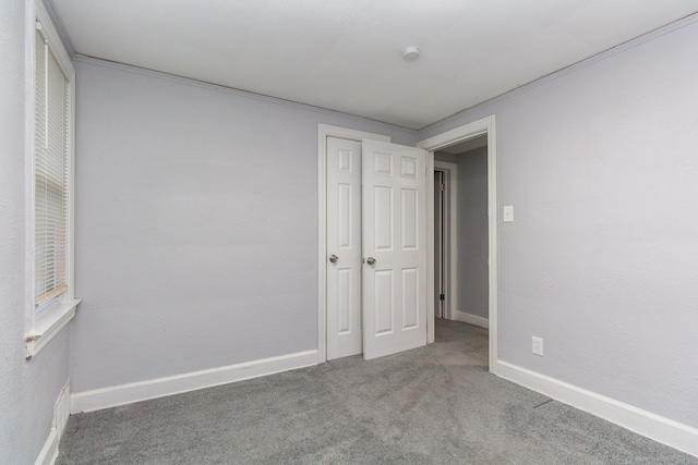 unfurnished bedroom with carpet flooring, a closet, and crown molding