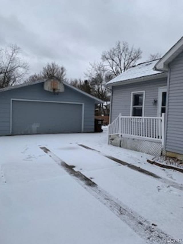 view of snow covered exterior with an outbuilding and a garage