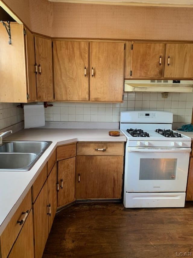 kitchen featuring dark hardwood / wood-style flooring, tasteful backsplash, white gas stove, and sink