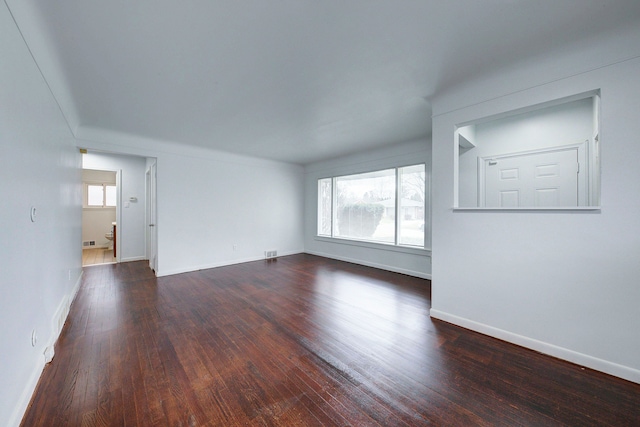 spare room with dark hardwood / wood-style flooring and a healthy amount of sunlight