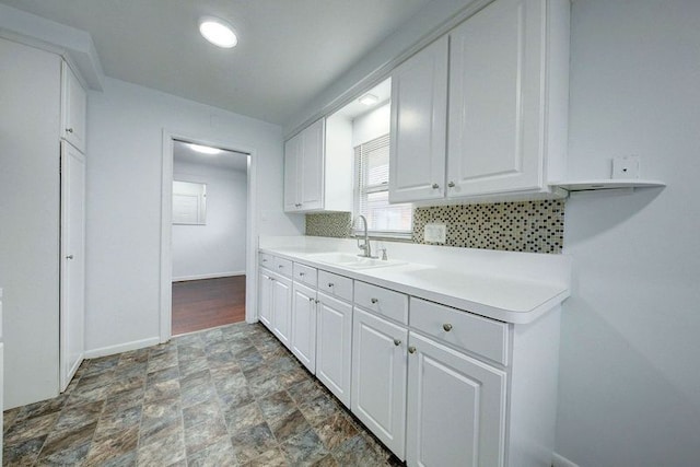 kitchen featuring decorative backsplash, white cabinetry, and sink