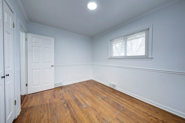 unfurnished bedroom featuring hardwood / wood-style flooring, ornamental molding, and a closet