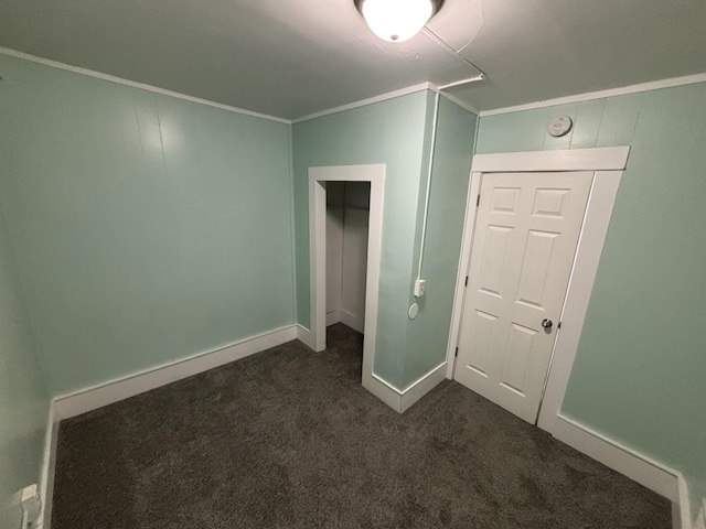 unfurnished bedroom featuring dark carpet, ornamental molding, and a closet