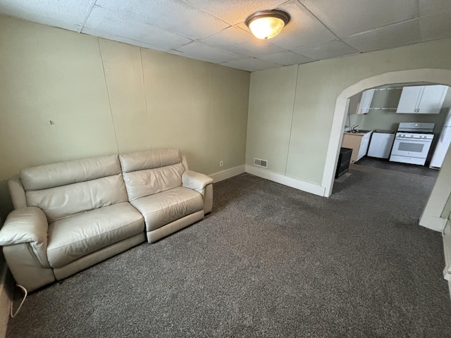 unfurnished living room with a drop ceiling and dark colored carpet