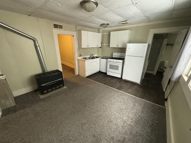 kitchen with a paneled ceiling, white appliances, dark colored carpet, sink, and white cabinetry