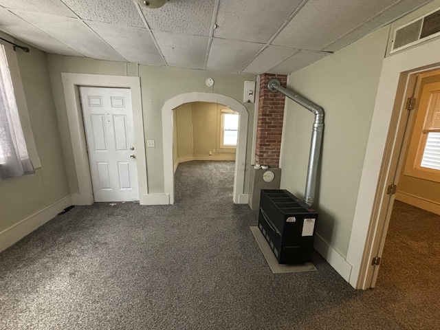 interior space featuring heating unit, dark carpet, and a drop ceiling