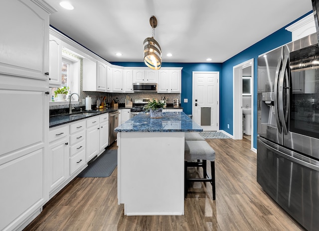 kitchen featuring white cabinets, sink, hardwood / wood-style flooring, a kitchen island, and stainless steel appliances