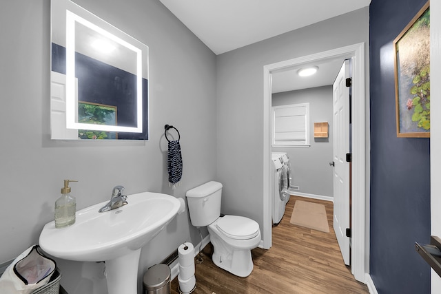 bathroom featuring hardwood / wood-style flooring, washer and dryer, toilet, and sink