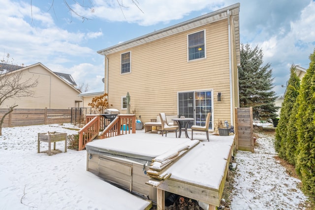 snow covered house featuring a covered hot tub