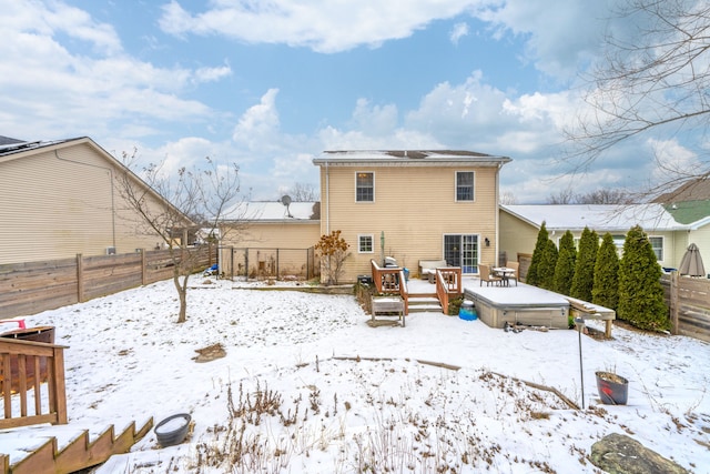 snow covered back of property with a deck