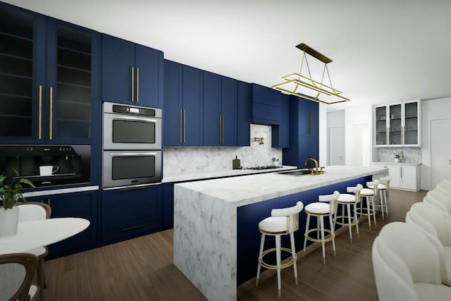 kitchen with a kitchen island with sink, decorative backsplash, dark hardwood / wood-style floors, decorative light fixtures, and a breakfast bar area