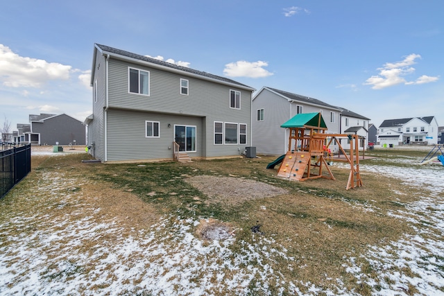 snow covered rear of property with a playground and central AC