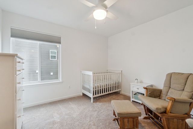 carpeted bedroom with ceiling fan and a crib