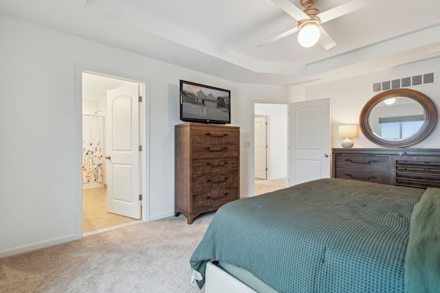 carpeted bedroom with ceiling fan and a raised ceiling