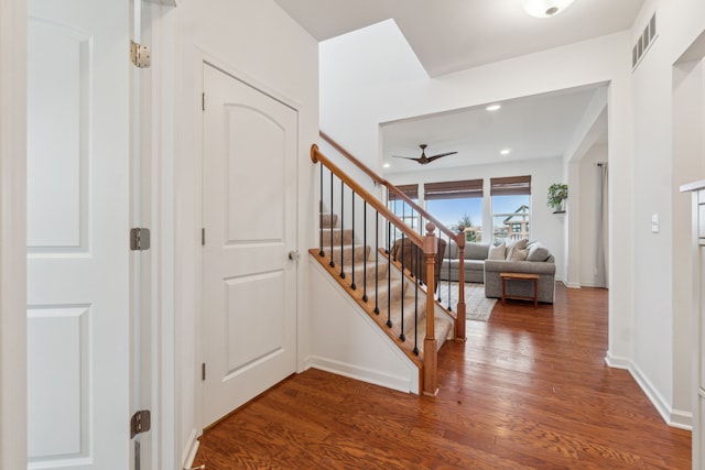 staircase with hardwood / wood-style floors and ceiling fan