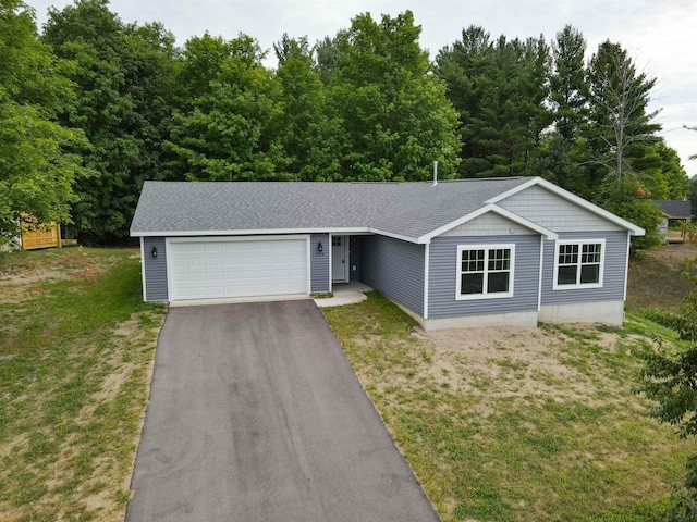 704 Eden St, Kingsley, MI 49649 - ranch-style house with an attached garage, asphalt driveway, a front lawn, and roof with shingles