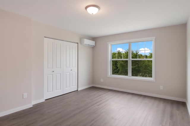 704 Eden St, Kingsley, MI 49649 - unfurnished bedroom featuring a wall mounted AC, wood finished floors, and a closet
