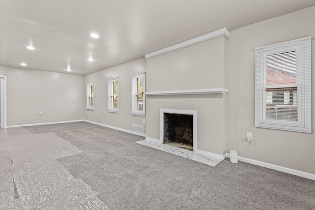 unfurnished living room featuring light carpet and a wealth of natural light